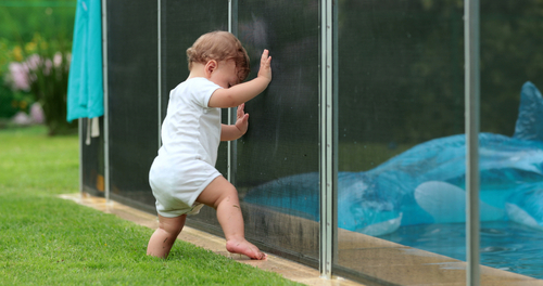 Toddler baby standing by swimming pool