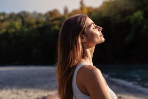 Young woman with long hair enjoying sun with closed eyes.